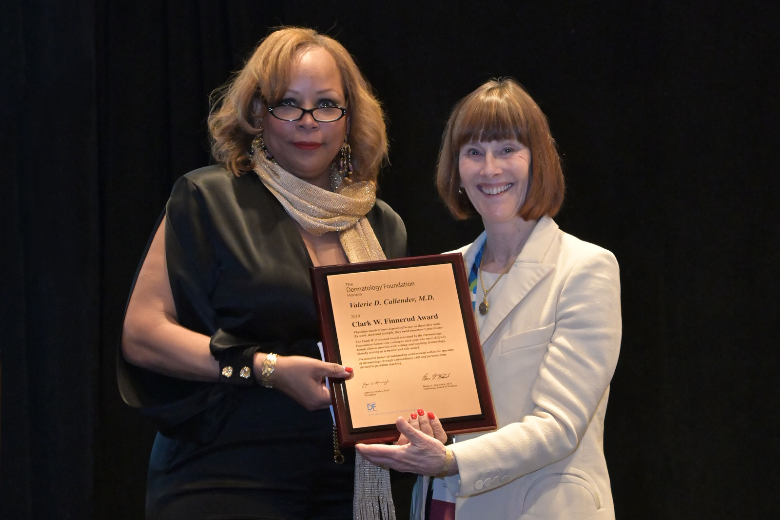Dr. Callender <i>(left)</i> receives the Clark W. Finnerud award from DF President Dr. Janet Fairley <i>(right)</i>. The award celebrates an individual who blends a clinical practice with writing and teaching dermatology.