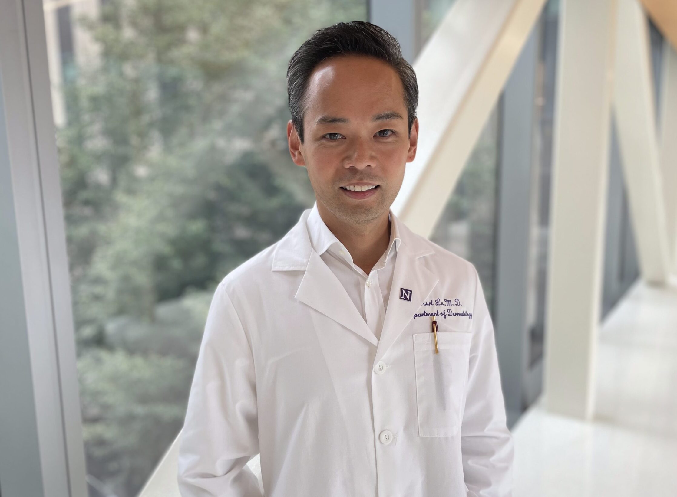 Dr. Kurt Lu, the Eugene and Gloria Bauer Professor of Dermatology at Northwestern University Feinberg School of Medicine and a Northwestern Medicine dermatologist. <I>Photo credit: Kristin Samuelson, Northwestern University</I>. Man standing in front of window.