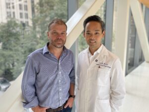 Two men standing in front of a window in a hospital.
