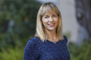 Close-up photo of a woman with blond hair wearing a royal blue sweater.