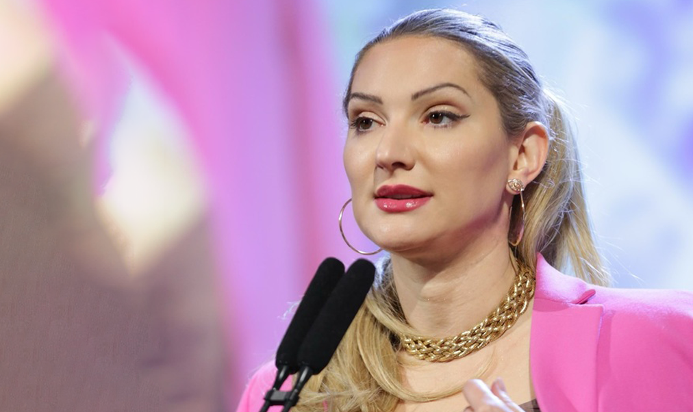 Headshot of a woman in pink jacket against a blurry background.